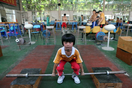 This picture taken on July 11, 2012 shows a young Chinese girl training at a weightlifting school in Xiamen, southeast China's Fujian province. Dominant China put Asia on top of the world at the Beijing Olympics but the pressure is on as they bid to repeat the feat away from home.      CHINA OUT      AFP PHOTO